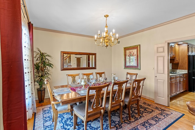 dining area featuring crown molding, light hardwood / wood-style flooring, and an inviting chandelier