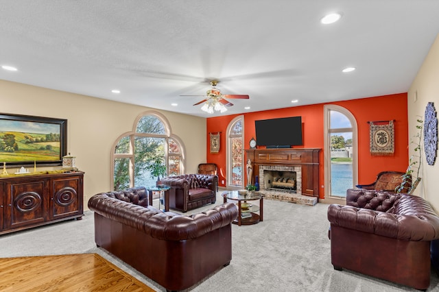 living room featuring ceiling fan, a brick fireplace, light wood-type flooring, and plenty of natural light