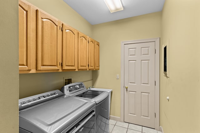 laundry area with washer and clothes dryer, light tile patterned flooring, and cabinets