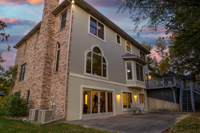 back house at dusk with a patio area, a wooden deck, and central AC unit