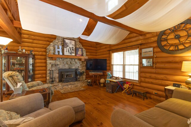 living room with lofted ceiling with beams, a wood stove, wood-type flooring, a stone fireplace, and rustic walls