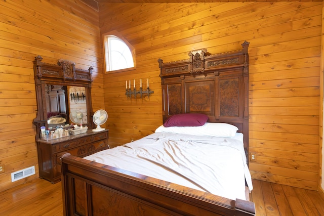 bedroom featuring light wood-type flooring and wood walls