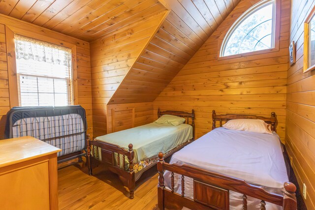 bedroom with light wood-type flooring, wood walls, and wood ceiling