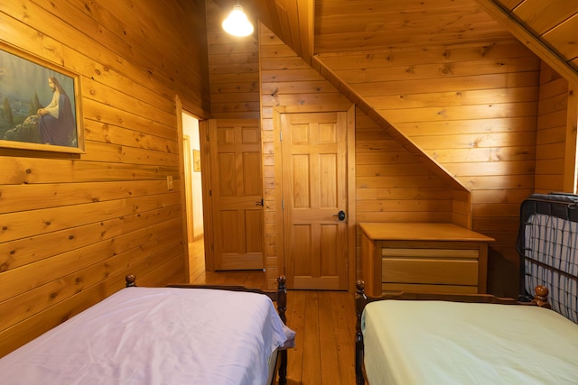 bedroom with vaulted ceiling, hardwood / wood-style flooring, and wooden walls