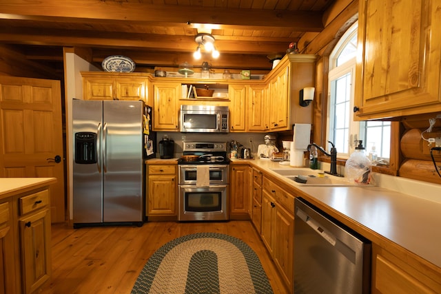 kitchen featuring light wood-type flooring, beamed ceiling, stainless steel appliances, sink, and wooden ceiling