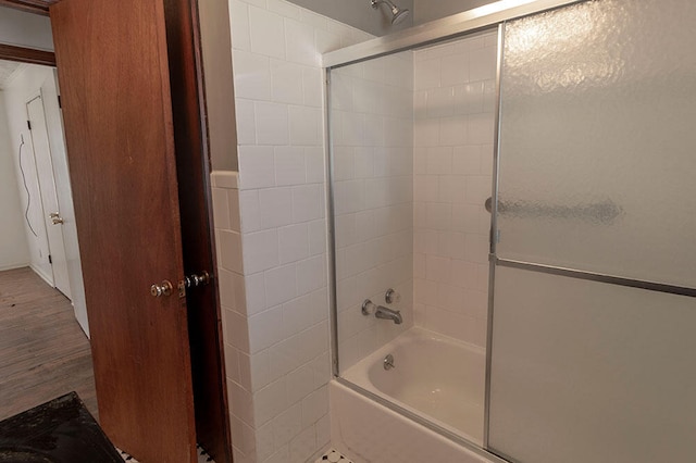 bathroom with hardwood / wood-style flooring and combined bath / shower with glass door