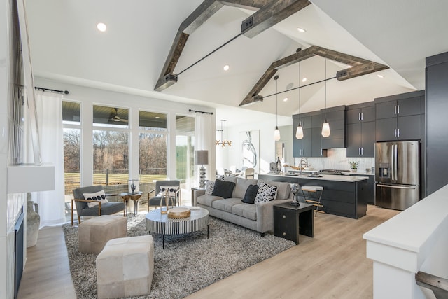 living room with high vaulted ceiling, light wood-type flooring, beamed ceiling, and sink