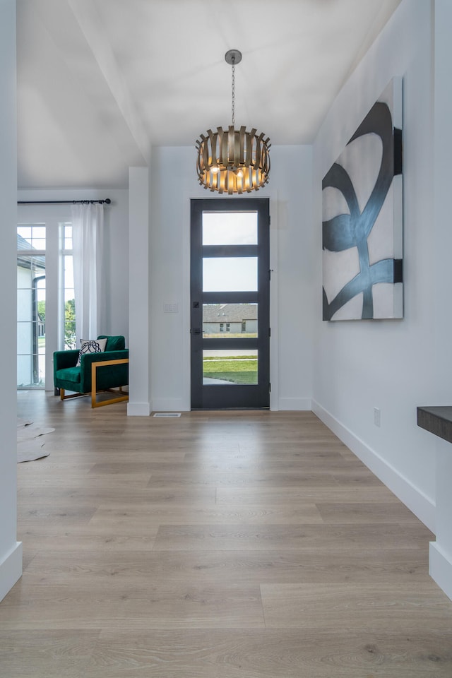 foyer featuring a healthy amount of sunlight, light hardwood / wood-style floors, and a notable chandelier