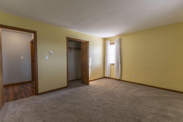 unfurnished bedroom featuring a closet, a textured ceiling, and dark colored carpet