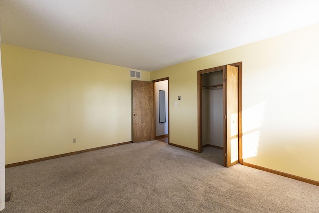 unfurnished bedroom with light colored carpet and a closet