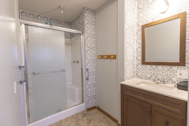 bathroom with a textured ceiling, vanity, and walk in shower