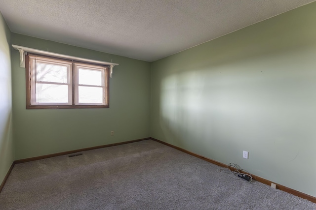 carpeted empty room featuring a textured ceiling