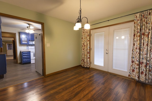 unfurnished dining area with french doors, ceiling fan with notable chandelier, and dark hardwood / wood-style floors