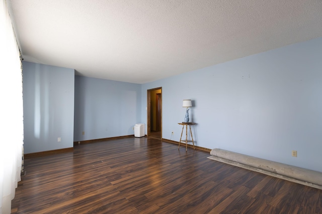 unfurnished room with a textured ceiling and dark wood-type flooring