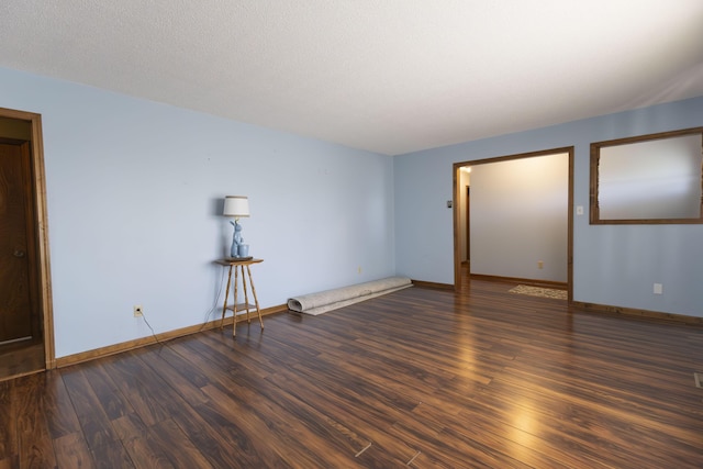 empty room with a textured ceiling and dark hardwood / wood-style floors