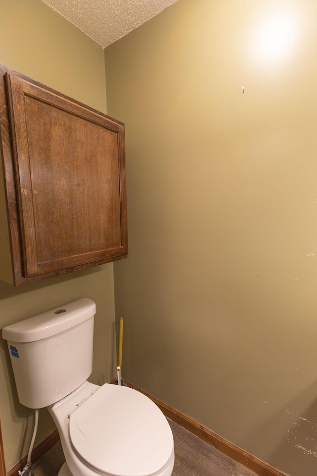 bathroom with wood-type flooring, a textured ceiling, and toilet