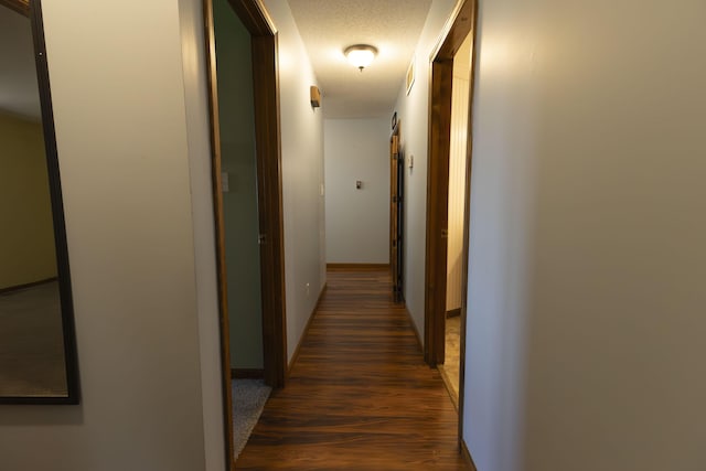 hall featuring a textured ceiling and dark wood-type flooring