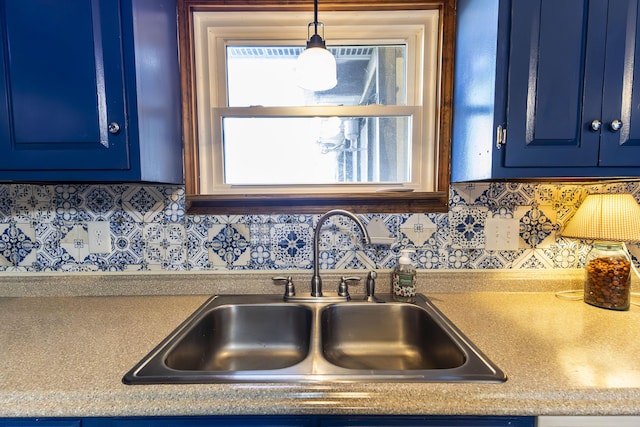 kitchen with backsplash, decorative light fixtures, blue cabinets, and sink