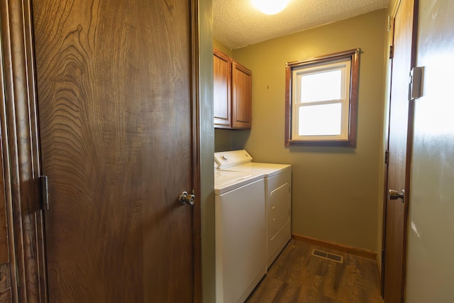 clothes washing area with dark hardwood / wood-style flooring, cabinets, a textured ceiling, and washing machine and dryer