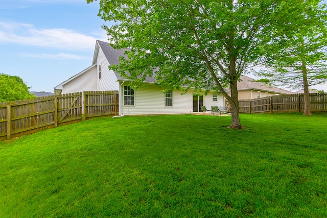 back of house featuring a yard, roof with shingles, and a fenced backyard