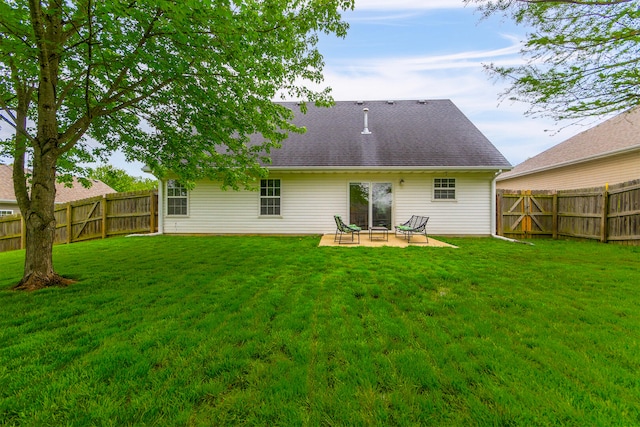 rear view of property with a fenced backyard, roof with shingles, a patio, and a yard