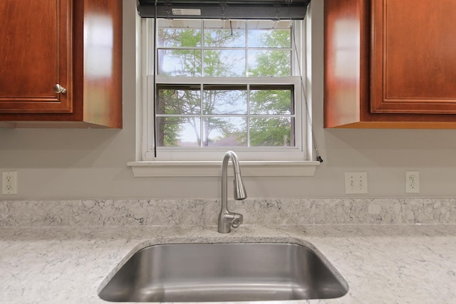 room details with light stone counters, brown cabinetry, and a sink