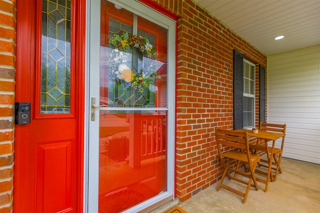entrance to property featuring a porch and brick siding