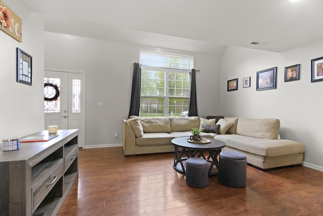 living area featuring lofted ceiling, plenty of natural light, dark wood-style floors, and visible vents