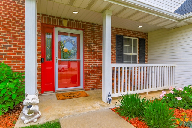 entrance to property with a porch and brick siding