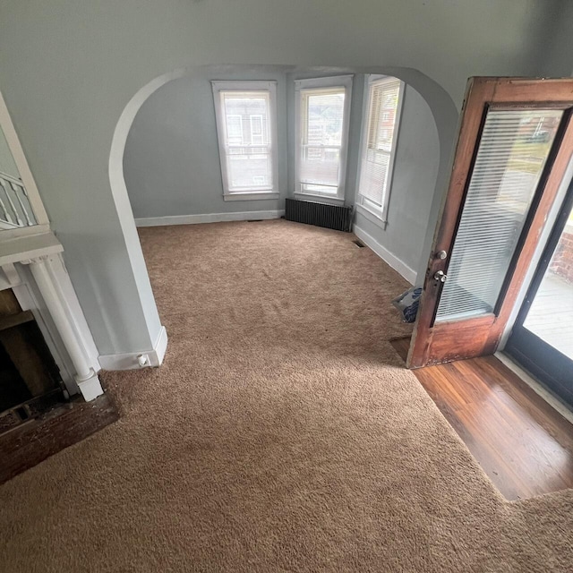 unfurnished living room featuring hardwood / wood-style floors and radiator heating unit