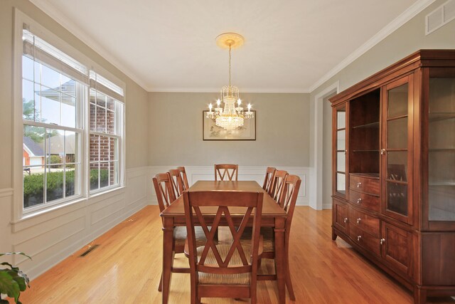 dining room with an inviting chandelier, crown molding, and light hardwood / wood-style flooring