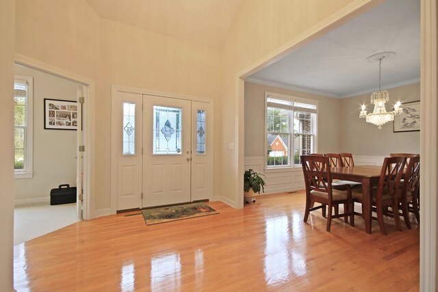 foyer entrance with light hardwood / wood-style floors, crown molding, and a notable chandelier