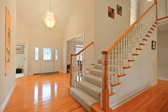 foyer featuring light wood-type flooring, a chandelier, and a high ceiling