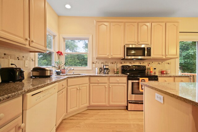 kitchen with light hardwood / wood-style floors, sink, appliances with stainless steel finishes, tasteful backsplash, and light stone countertops