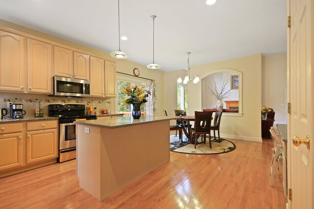 kitchen with stainless steel appliances, light hardwood / wood-style floors, a center island, decorative backsplash, and pendant lighting