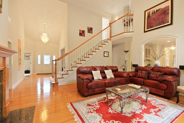 living room featuring hardwood / wood-style floors, a notable chandelier, crown molding, and a towering ceiling