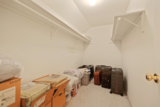 walk in closet with light carpet and vaulted ceiling