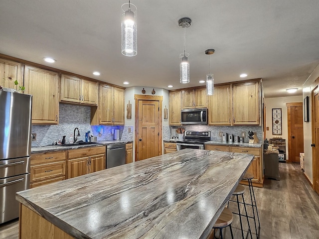 kitchen featuring dark wood-type flooring, sink, a kitchen island, stainless steel appliances, and backsplash