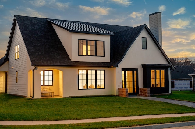 back house at dusk featuring a yard and french doors