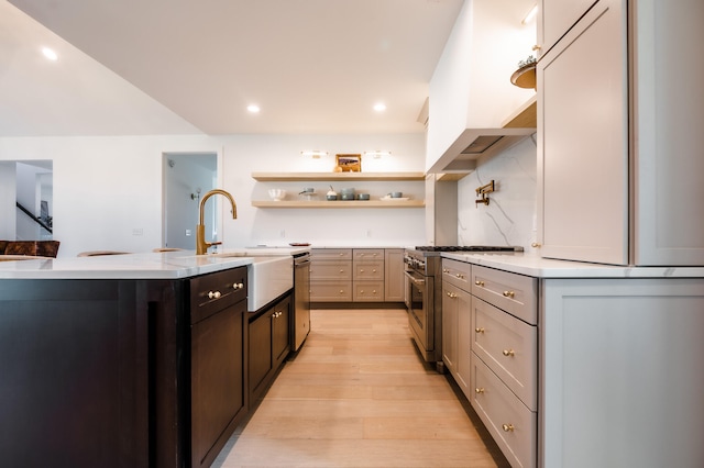 kitchen featuring appliances with stainless steel finishes, gray cabinetry, a kitchen island with sink, and light hardwood / wood-style flooring