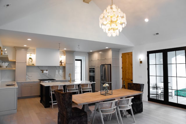 dining area featuring a notable chandelier, lofted ceiling, light wood-type flooring, and sink