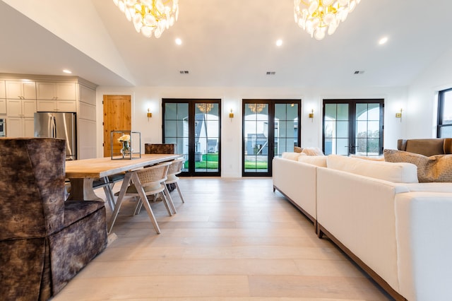 living room featuring french doors, vaulted ceiling, a chandelier, and a healthy amount of sunlight