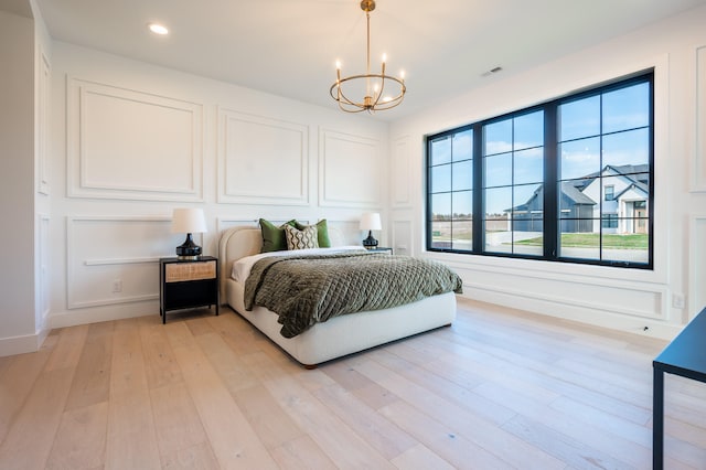 bedroom with light hardwood / wood-style flooring and an inviting chandelier