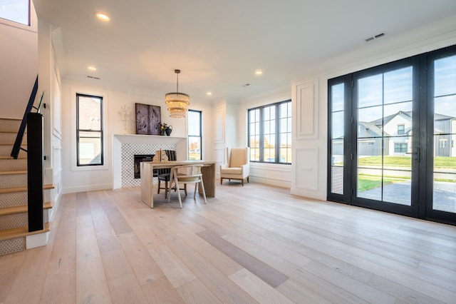 dining room featuring light wood-type flooring, crown molding, and a tile fireplace