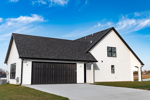 view of front of house with a garage, a front lawn, and central AC unit