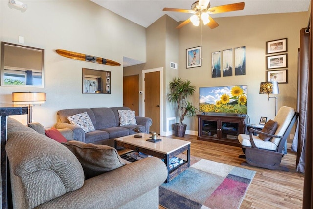 living room featuring ceiling fan, light wood-type flooring, and vaulted ceiling