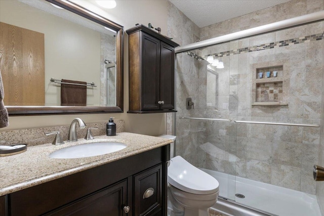 bathroom featuring a textured ceiling, vanity, toilet, and a shower with shower door