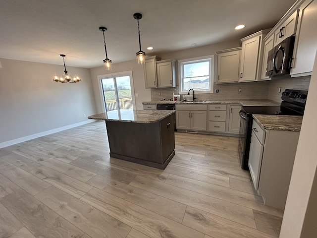 kitchen featuring a center island, sink, pendant lighting, decorative backsplash, and black appliances