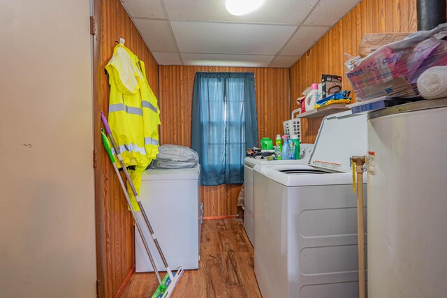 laundry area featuring light hardwood / wood-style floors, water heater, wooden walls, and washer and clothes dryer