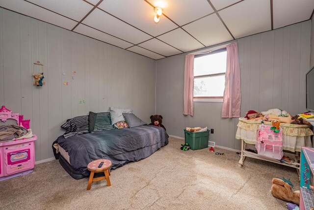 carpeted bedroom featuring a drop ceiling and wooden walls